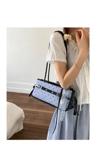 Detail of light blue polka dot shoulder bag with black heart patterns and buckle strap