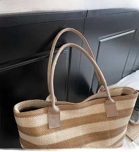 Detail of striped woven tote bag featuring reinforced handles and raffia texture