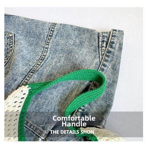 Detail view showing green and white woven handle on blue denim fabric with neat stitching