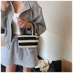 Detail of black and white striped woven tote bag with chain strap and flower charm