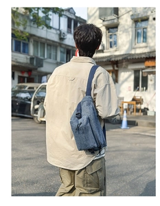 Detailed view of gray-blue washed denim chest bag with durable strap and buckle