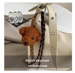 Détail d'un charme de sac chiot en peluche marron avec cordon tressé sur sac à main beige