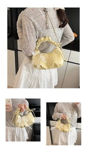 Detail of light yellow ruched cloud bag featuring a large white lace bow and metal chain
