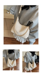 Detail of creamy white crescent hobo bag with gold chain strap shown on a model