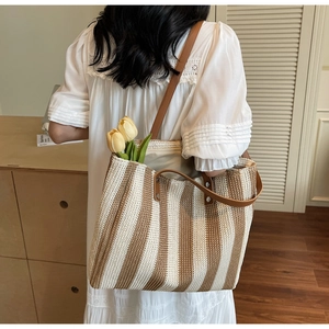 Detailed texture of a striped woven tote bag with brown leather straps for summer