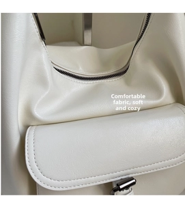 Detailed macro view of the cream leather texture and smooth metal zipper on the tote bag