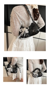 Detail of black patent leather crescent bag with pearl bow and white lace trim accents