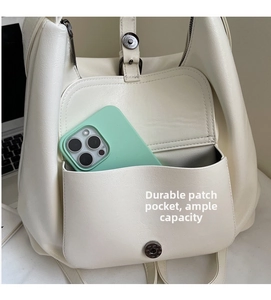 Detail of cream leather tote backpack showing a durable side pocket fitting a smartphone