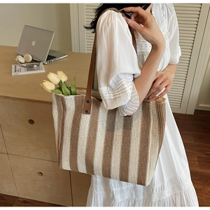 Detail of striped woven tote bag with brown leather handles and yellow tulips
