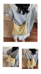 Detail view of yellow hobo bag with pebbled leather texture and chunky gold chain strap