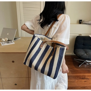 Macro view of blue and white striped straw tote with premium brown leather straps