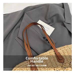 Detail of leather handles with white stitching on straw woven shoulder bag for vacation