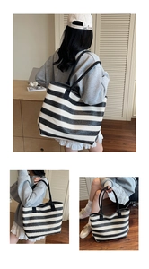Detail of a large black and white striped woven tote bag with sturdy black handles