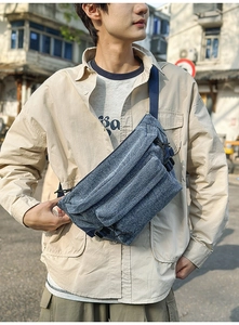 Detail of blue washed denim sling bag with adjustable strap and buckle on outdoor model