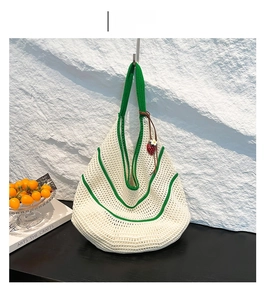 Detail of woven beach bag in off-white and green with strawberry and daisy charms