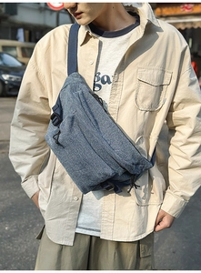 Detail of blue denim sling bag with reinforced adjustable straps and premium zipper puller