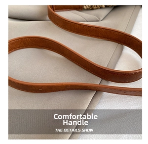 Detailed macro view showing premium brown leather texture and neat stitching of the bag handle