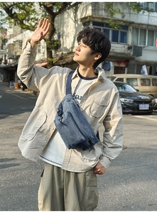 Blue washed denim sling bag for men worn by model in a natural urban outdoor setting