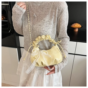 Detail of soft yellow cloud bag with lace bow and silver chain strap on model