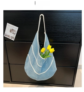 Detailed blue hand-woven crochet bag with white contrast piping and soft curved silhouette