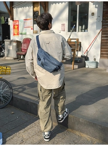 Detail view of the washed denim crossbody bag worn by a model in an outdoor setting