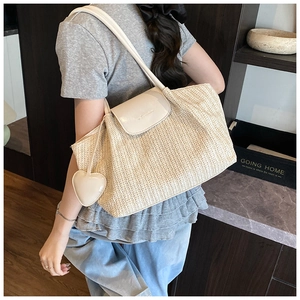 Detail of hand-woven tote bag with V-shaped pattern, cream leather flap and heart pendant