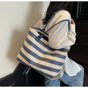 Close-up of blue and white striped woven tote bag with fine straw texture detail