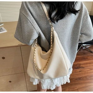 Close-up of cream white hobo bag showing lychee grain texture and metal chain strap