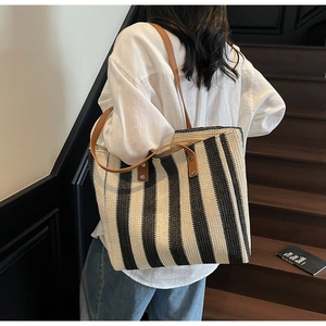 Detail of black and white striped woven tote with brown leather straps and rivet accents