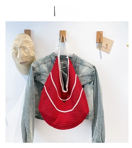 Close-up of red crochet knit shoulder bag with white stripes hanging on a wall hook
