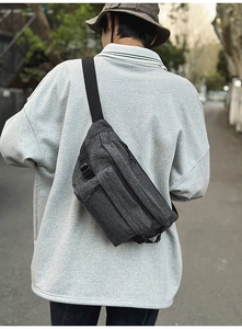 Detailed view of the dark grey denim chest bag with adjustable nylon straps and buckle