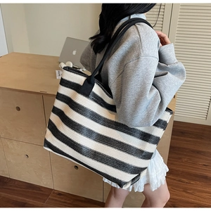 Detail of black and white striped woven tote bag showing large capacity and fabric handle