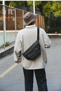 Macro shot of grey washed denim crossbody bag worn by a model in a street setting