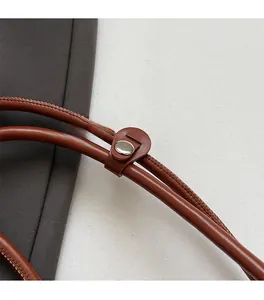 Detail of premium brown leather shoulder strap with polished silver metal buckle and stitching