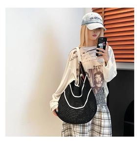 Detail of a black and white crochet shoulder bag with moon-shaped weaving and wide strap