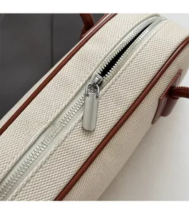 Close-up of smooth silver zipper on a beige canvas bowling bag with brown leather trim