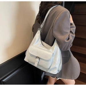 Detail of light blue tote bag with buckle pocket shown on a model in urban setting