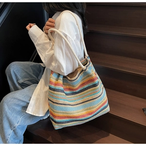 Détail d'un sac cabas tissé coloré avec des anses en corde sur un escalier en bois