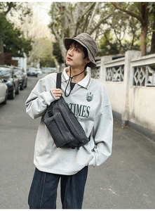 Outdoor male model wearing a dark grey vintage washed denim crossbody bag and a bucket hat