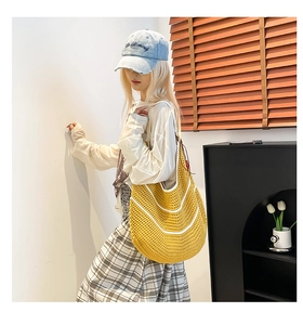 Detail of yellow hand-crocheted shoulder bag with white curved contrast stripes on a model