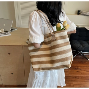 Detailed view of striped woven tote bag featuring deep brown and beige straw texture