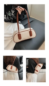Detail of a large cream canvas bowling bag with brown leather handles and silver zipper
