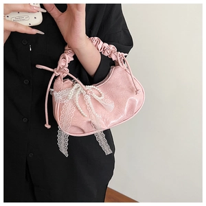 Close-up of pink patent leather cloud bag with lace ribbons and pearl butterfly details