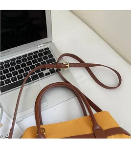 Détail du sac cabas en toile jaune avec bandoulière en cuir marron et boucles dorées