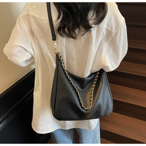 Detail of black lychee grain hobo bag with gold chain strap shown on a model