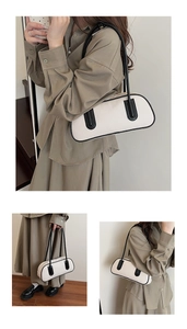 Detail of a chic cream bowling bag with black contrast trim and slim shoulder straps