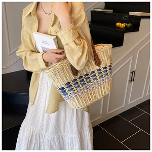 Detail of hand-woven straw tote bag with colorful diamond pattern and leather straps