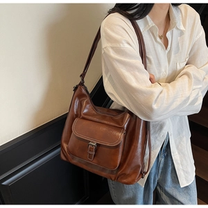 Detail of dark brown leather tote bag with metallic buckle pocket and vintage texture