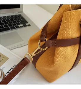 Détail de la ferrure dorée et du canevas moutarde sur ce sac à main élégant