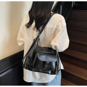 Detail of black tote bag with white stitching and decorative buckle on front pocket